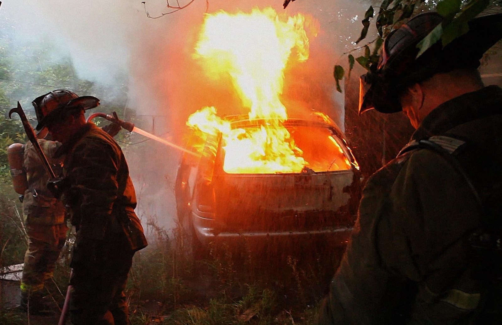 Detroit firefighters hosing down a fully engulfed car fire during BURN