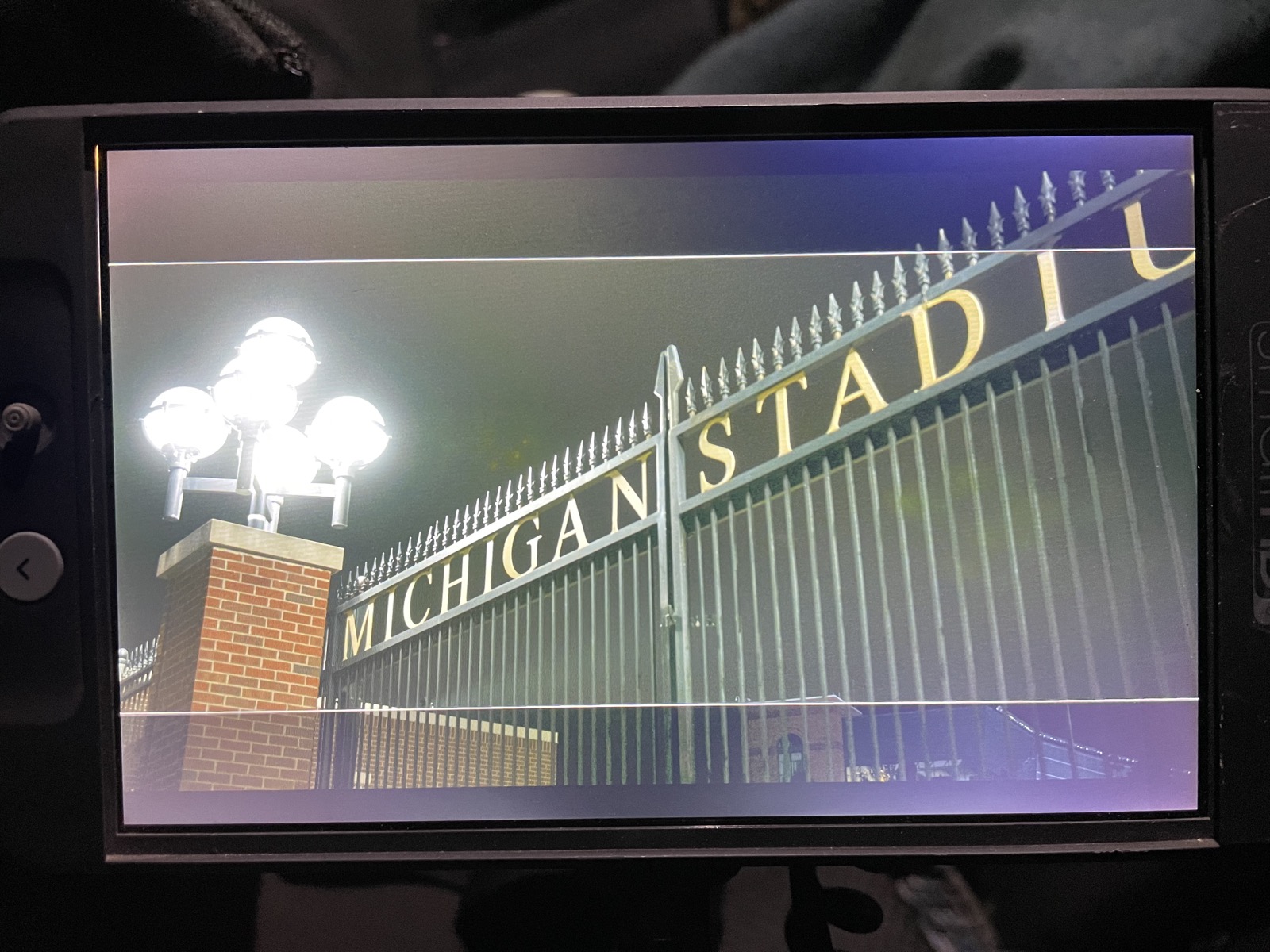 Camera monitor showing the gilded Michigan Stadium lettering being filmed at dusk during Hail To The Victims production